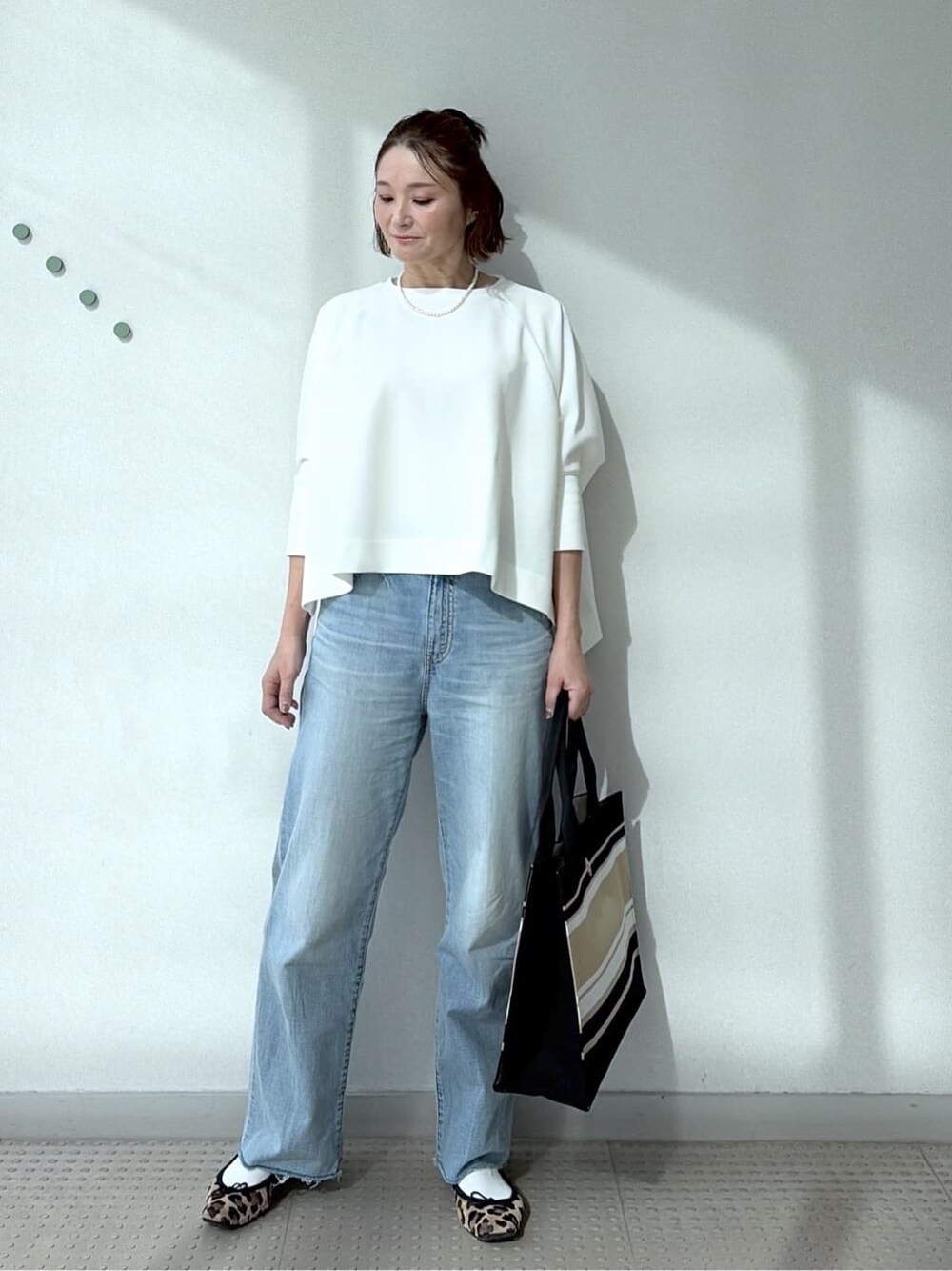 ホワイト系のTシャツ/カットソー、ブルー系のデニムパンツ、ブラック系のトートバッグを着用したレディースの冬コーディネートの1枚目の写真
