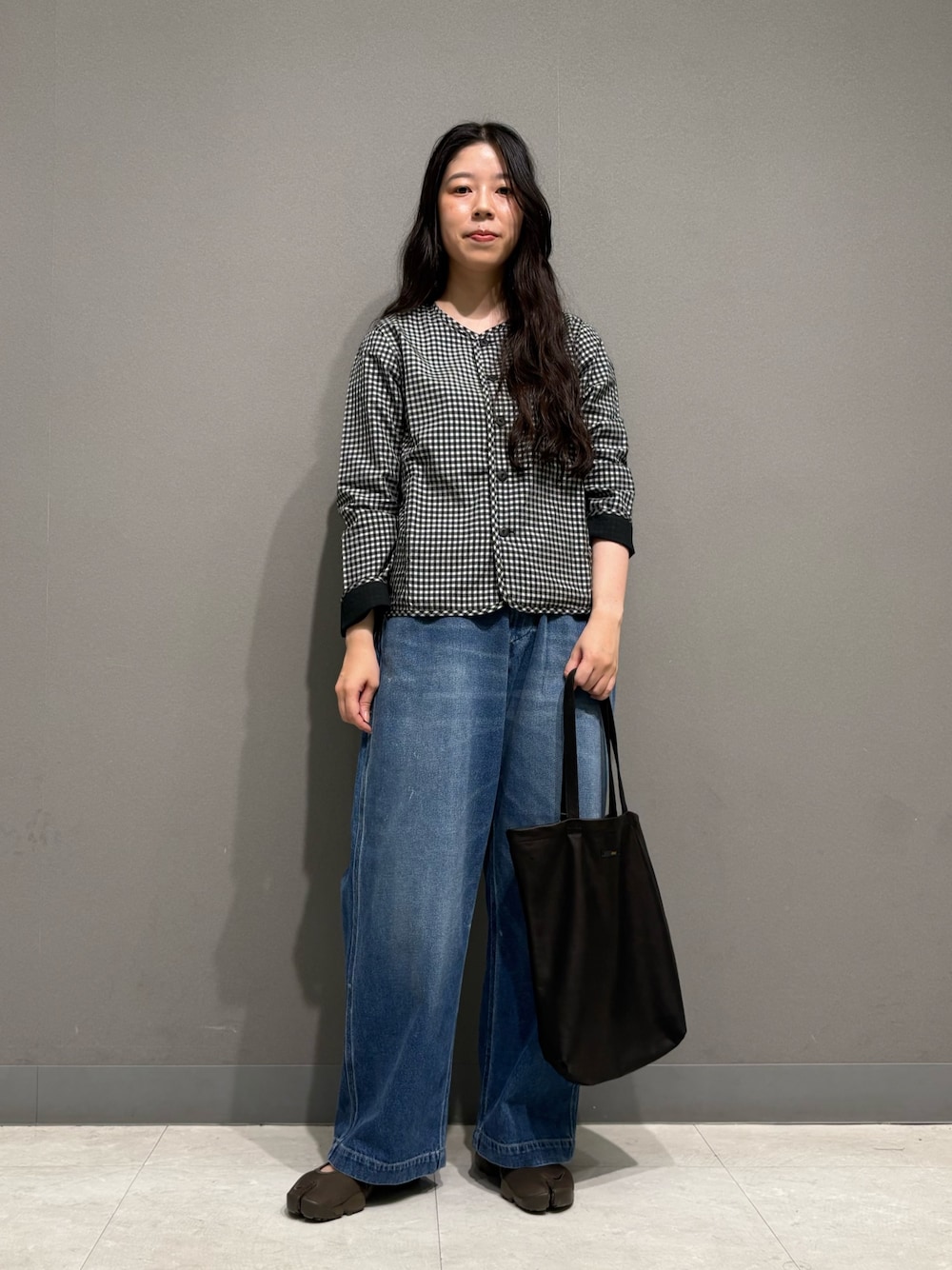 ブルー系のデニムパンツ、ブラック系のノーカラージャケット、ブラック系のトートバッグを着用したレディースの夏コーディネートの1枚目の写真