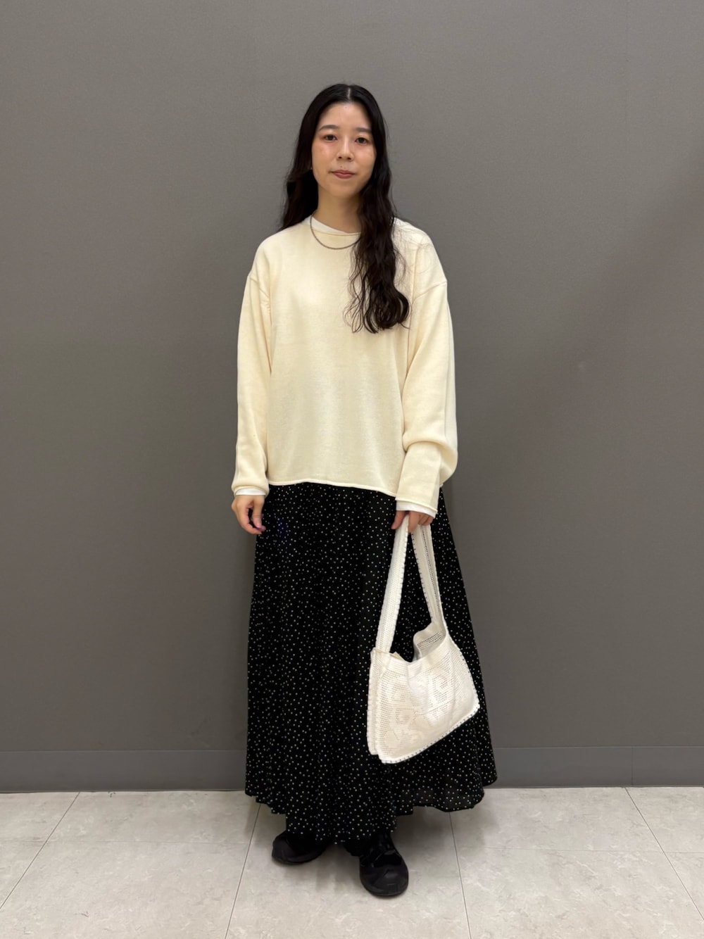 ホワイト系のニット/セーター、ホワイト系のTシャツ/カットソー、ブラック系のスカートを着用したレディースの秋コーディネートの1枚目の写真