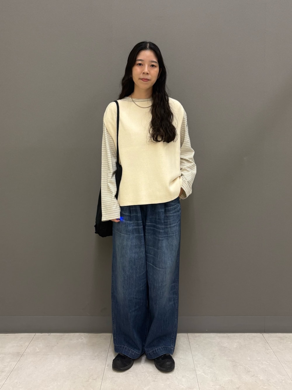 ホワイト系のベスト、ブルー系のデニムパンツ、ブラック系のトートバッグを着用したレディースの秋コーディネートの1枚目の写真