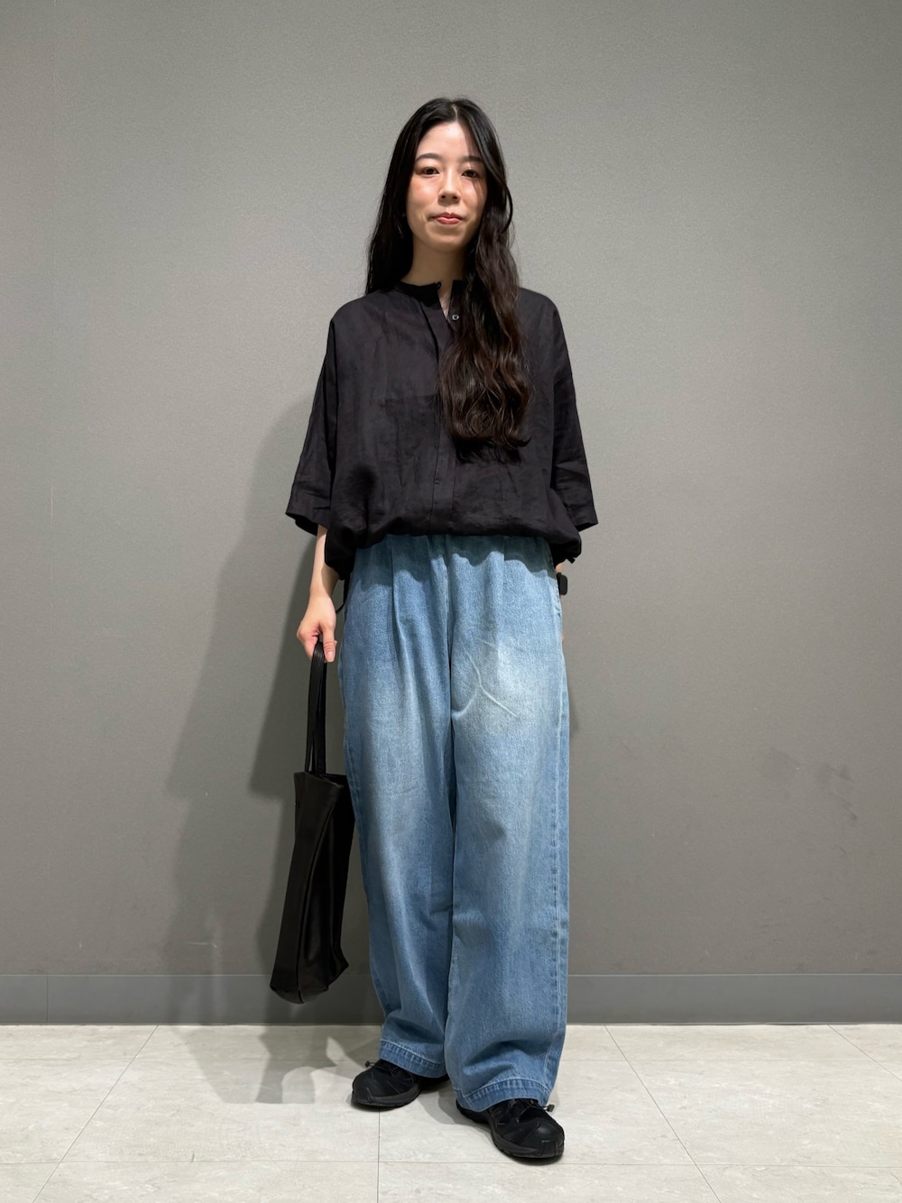 ブラック系のシャツ/ブラウス、ブラック系のトートバッグ、ブルー系のデニムパンツを着用したレディースの夏コーディネートの1枚目の写真
