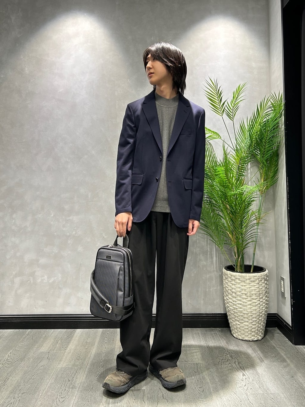 グレー系のニット/セーター、ブルー系のテーラードジャケット、グレー系のショルダーバッグを着用したメンズの秋コーディネートの1枚目の写真