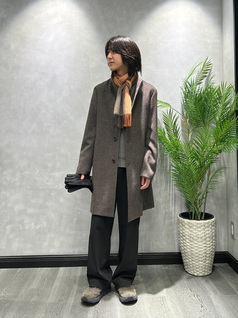ブラウン系のその他アウター、グレー系のニット/セーター、オレンジ系のマフラーを着用したメンズの秋コーディネートの1枚目の写真