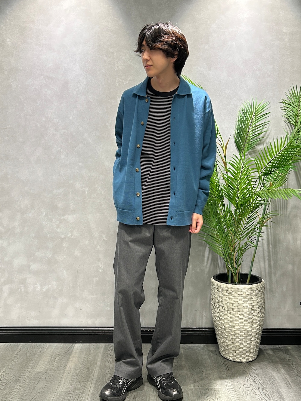ブルー系のニット/セーター、ブラック系のTシャツ/カットソー、グレー系のスラックスを着用したメンズの秋コーディネートの1枚目の写真