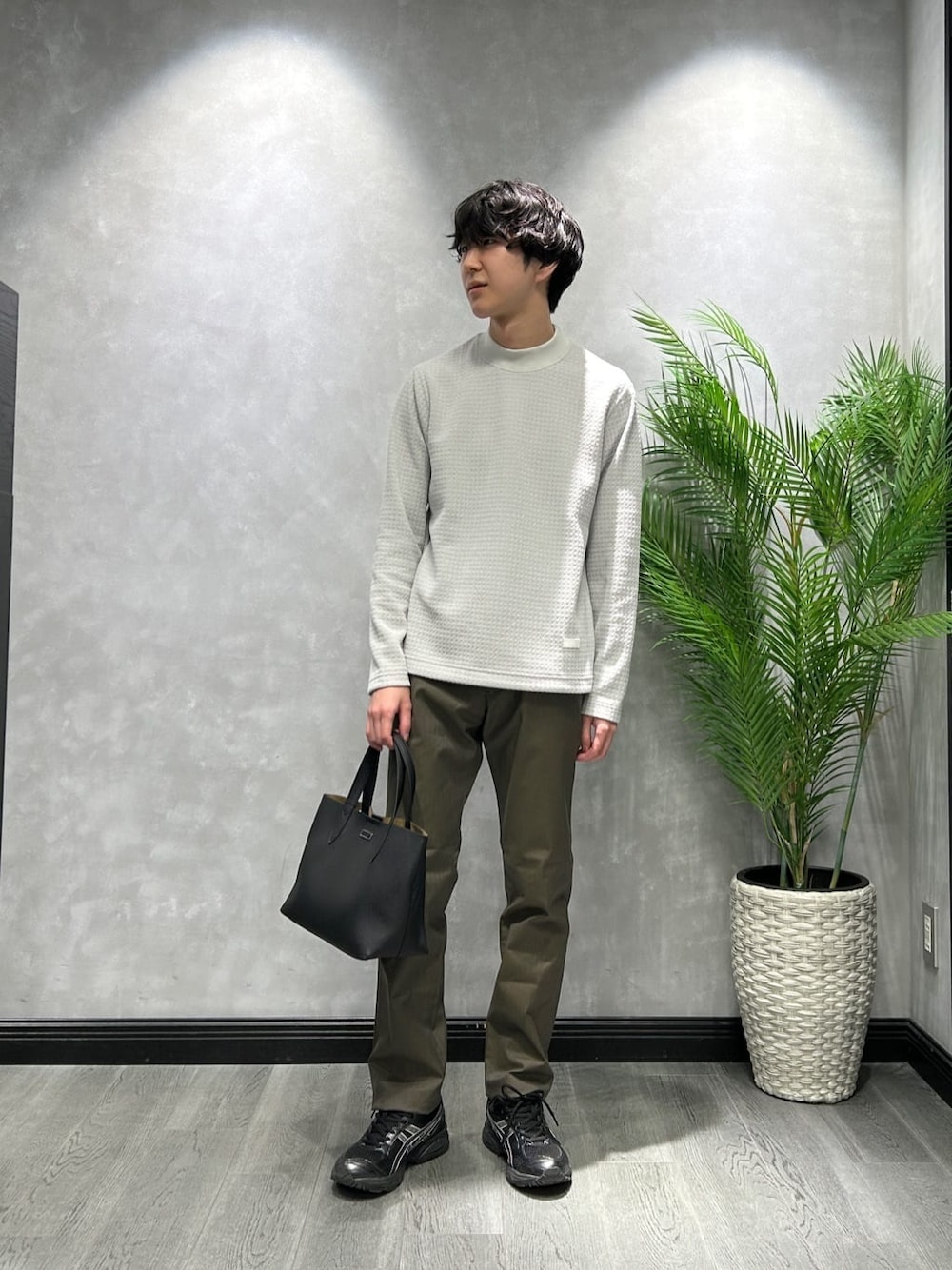 グレー系のTシャツ/カットソー、グリーン系のスラックス、ブラック系のトートバッグを着用したメンズの冬コーディネートの1枚目の写真