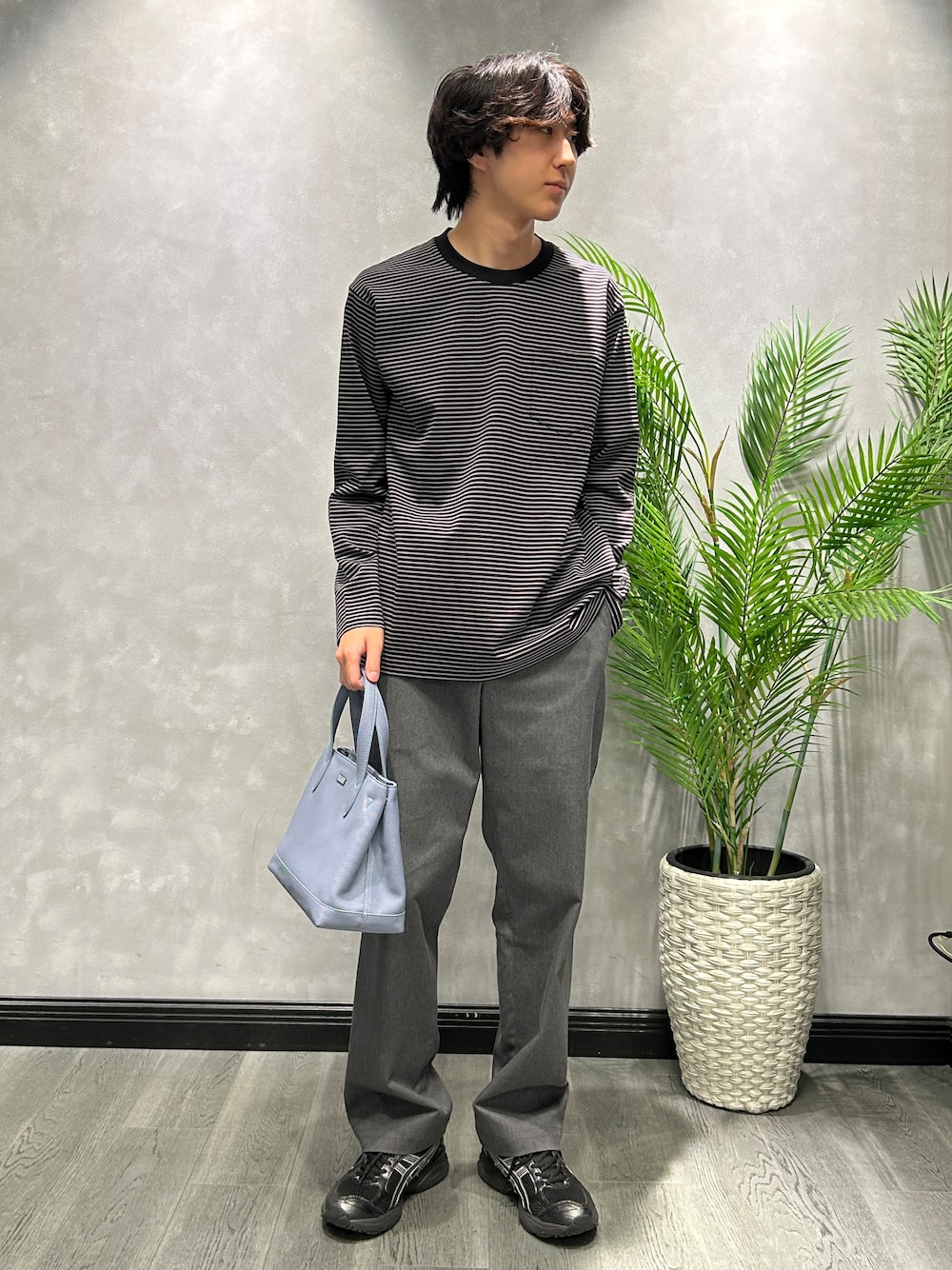 ブラック系のTシャツ/カットソー、グレー系のスラックス、ブルー系のトートバッグを着用したメンズの秋コーディネートの1枚目の写真