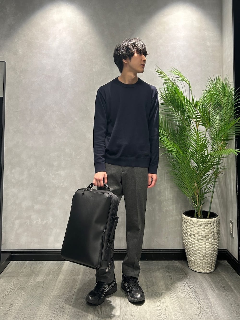 ブルー系のニット/セーター、ブラック系のスラックス、ブラック系のバックパック/リュックを着用したメンズの冬コーディネートの1枚目の写真