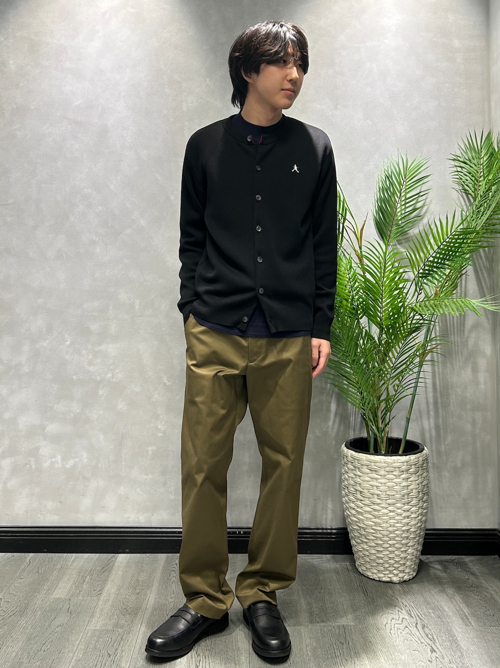 ブラック系のカーディガン/ボレロ、ブルー系のニット/セーター、グリーン系のスラックスを着用したメンズの秋コーディネートの1枚目の写真