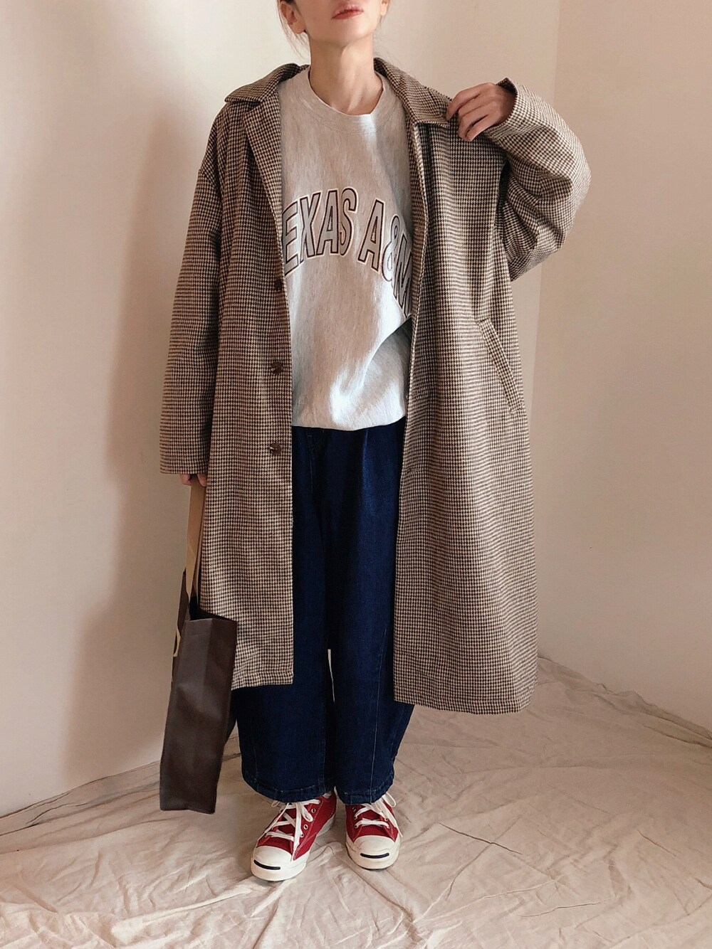 ブラウン系のステンカラーコート、グレー系のスウェット、ブルー系のデニムパンツを着用したレディースの秋コーディネートの1枚目の写真