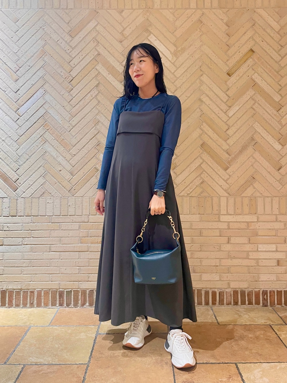 グリーン系のショルダーバッグ、ホワイト系のスニーカーを着用したレディースの秋コーディネートの1枚目の写真