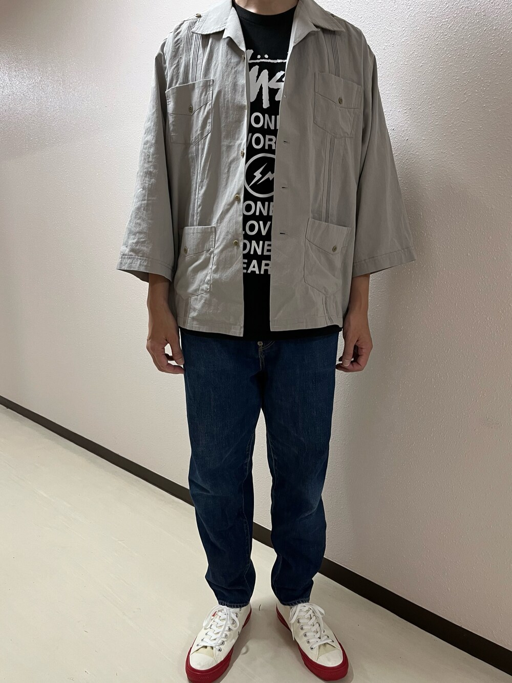 ブルー系のデニムパンツ、ホワイト系のスニーカー、ブラック系のTシャツ/カットソーを着用したメンズの夏コーディネートの1枚目の写真