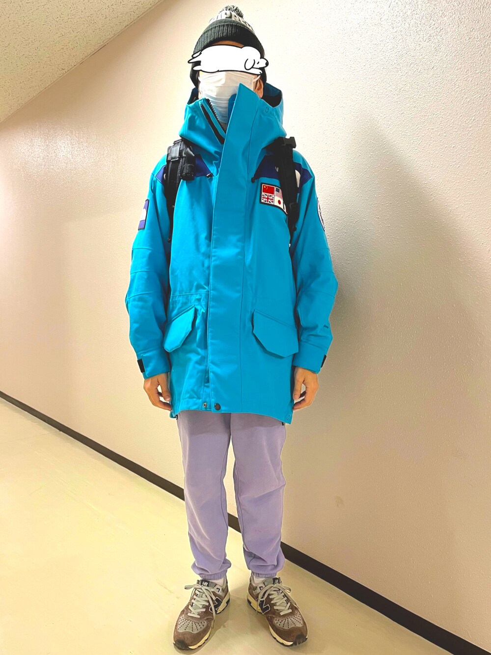 パープル系のスウェットパンツ、グレー系のスニーカー、ブルー系のマウンテンパーカーを着用したメンズの冬コーディネートの1枚目の写真