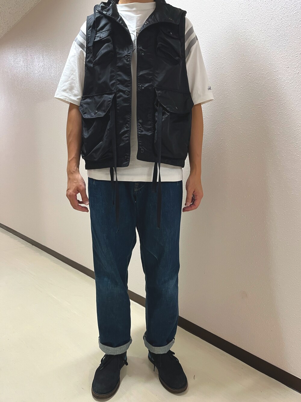 ブルー系のデニムパンツ、ブラック系のブーツ、ブラック系のベストを着用したメンズの秋コーディネートの1枚目の写真