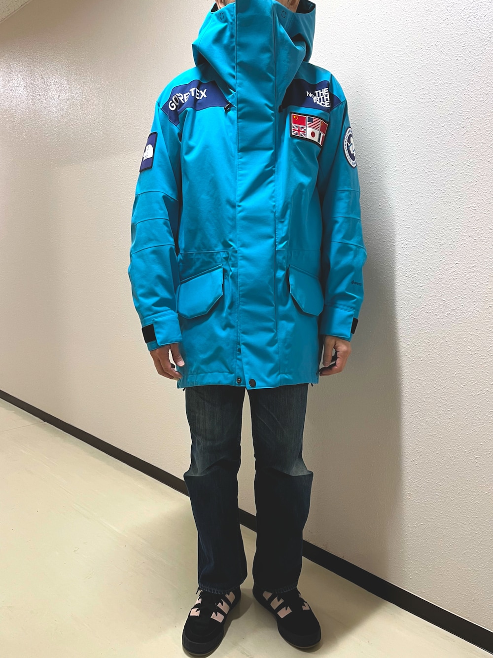 ブルー系のデニムパンツ、ブラック系のスニーカー、ブルー系のマウンテンパーカーを着用したメンズの冬コーディネートの1枚目の写真