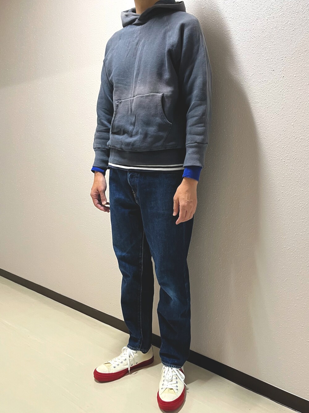 ブラック系のパーカー、ブルー系のデニムパンツ、ホワイト系のスニーカーを着用したメンズの秋コーディネートの1枚目の写真