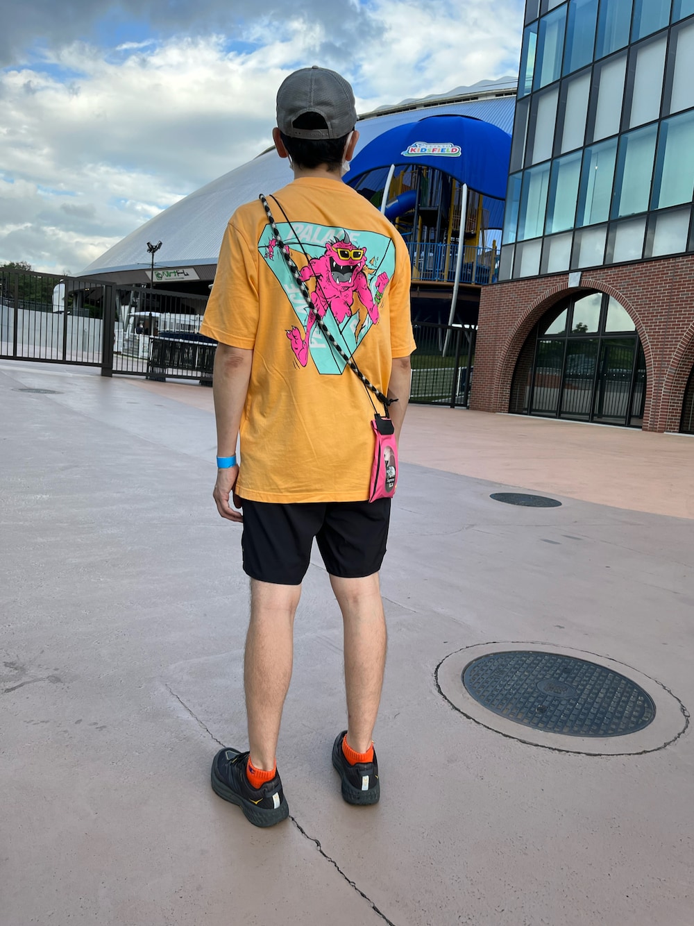 オレンジ系のTシャツ/カットソー、ブラック系のその他パンツ、ブラック系のスニーカーを着用したメンズの夏コーディネートの1枚目の写真