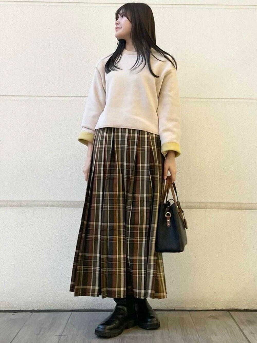 グリーン系のスカート、ホワイト系のニット/セーターを着用したレディースの冬コーディネートの1枚目の写真