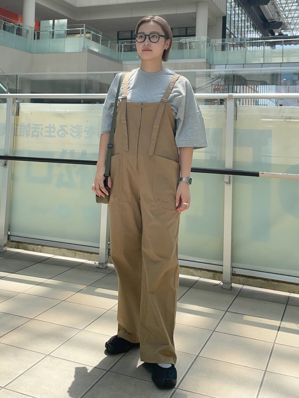 グリーン系のショルダーバッグ、イエロー系のサロペット/オーバーオール、グレー系のTシャツ/カットソーを着用したレディースの夏コーディネートの1枚目の写真