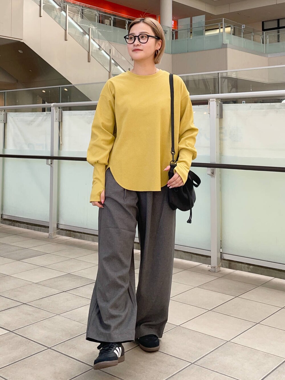 ブラック系のショルダーバッグ、ブラック系のスニーカー、イエロー系のTシャツ/カットソーを着用したレディースの秋コーディネートの1枚目の写真