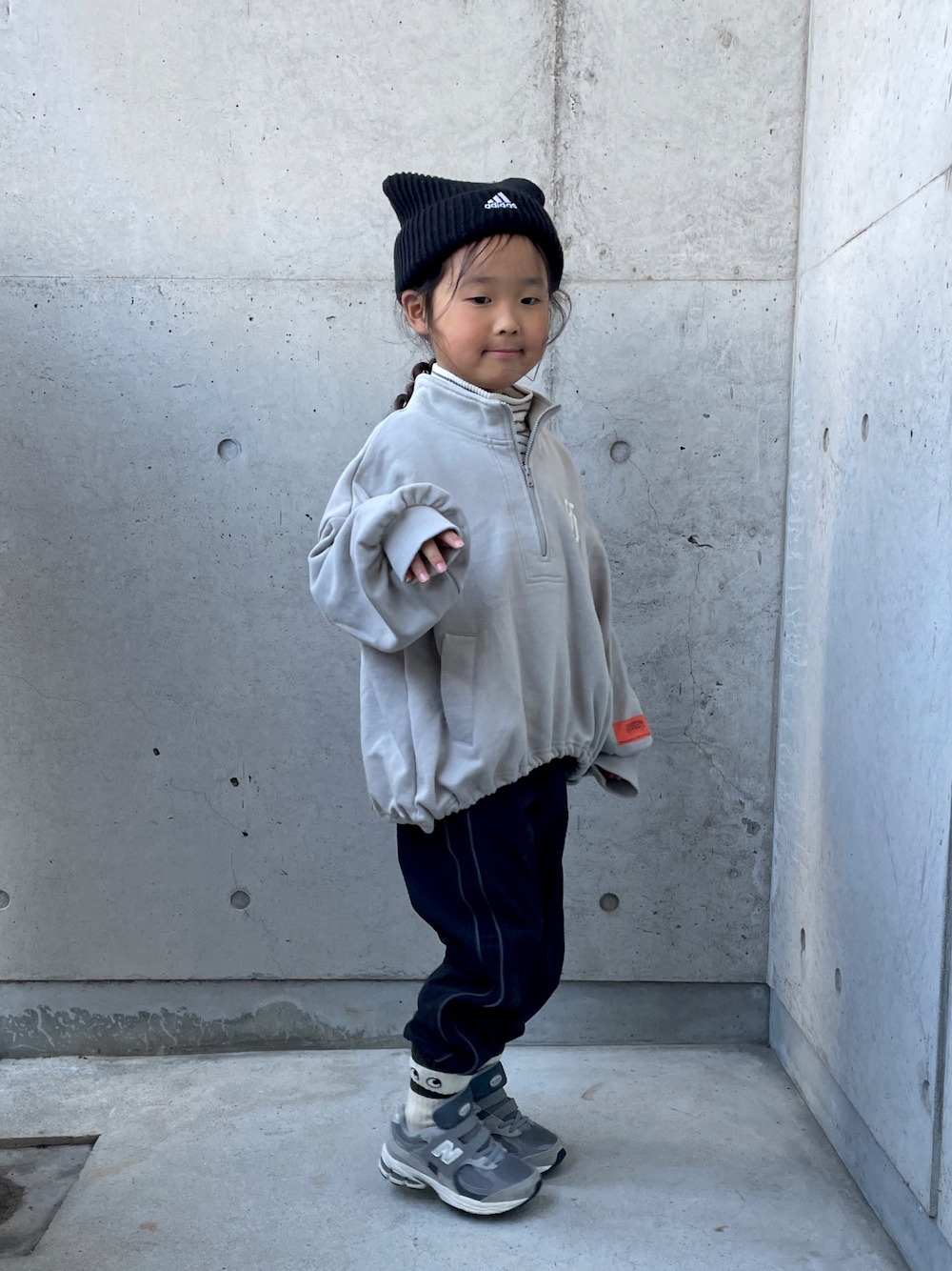 ブラック系のパンツ、ホワイト系のトップス、グレー系のスウェットを着用したキッズの冬コーディネートの1枚目の写真