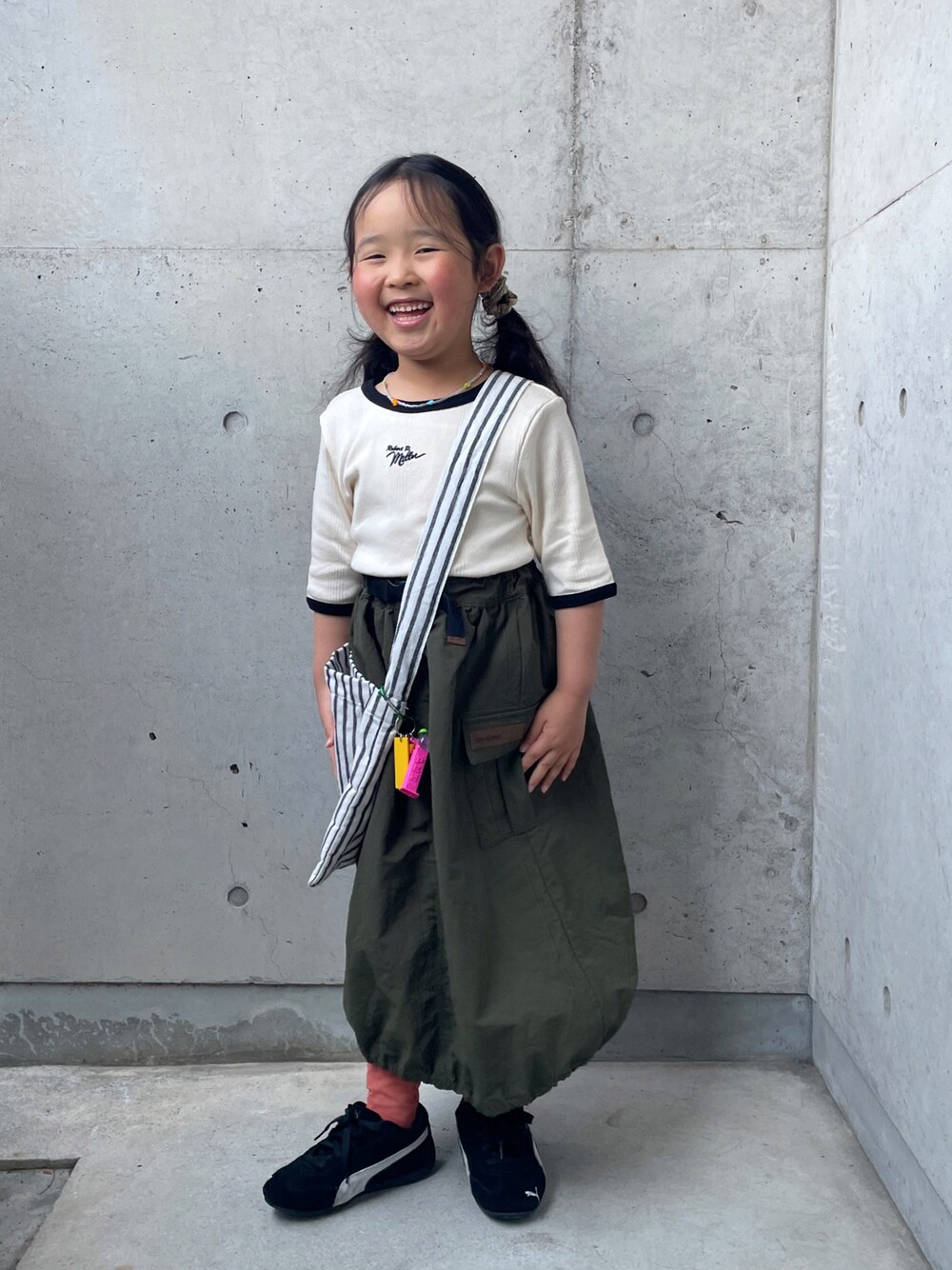 ホワイト系のTシャツ/カットソー、グリーン系のスカート、ブラック系のスニーカーを着用したキッズの春コーディネートの1枚目の写真