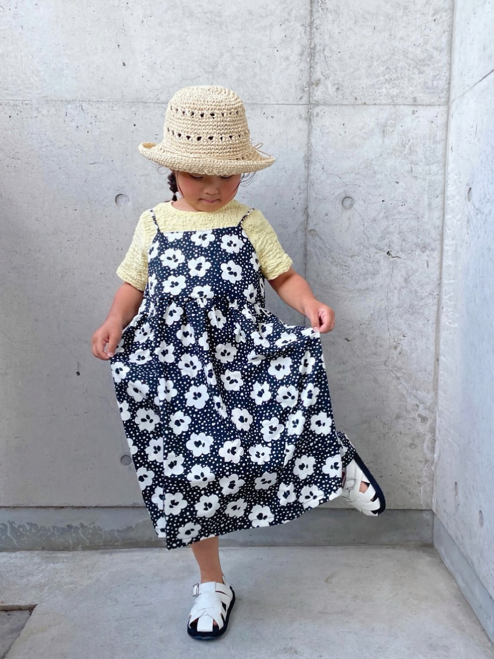 ブラック系のワンピース、ホワイト系のサンダル、ベージュ系のTシャツ/カットソーを着用したキッズの春コーディネートの1枚目の写真