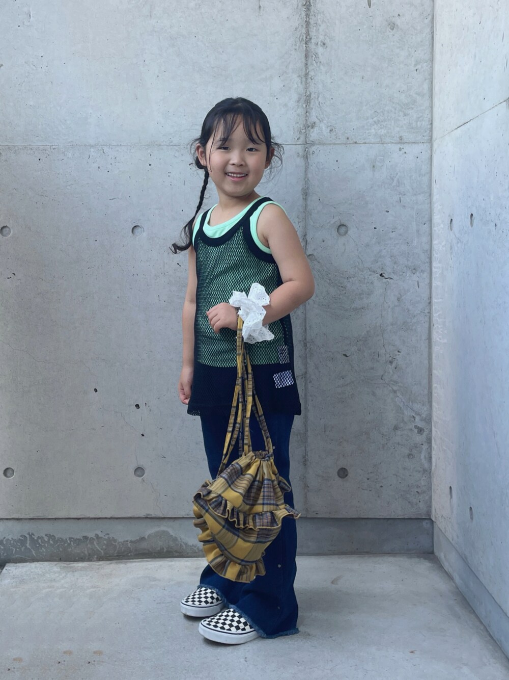 ブラック系のタンクトップ、ブルー系のデニムパンツ、イエロー系のバックパック/リュックを着用したキッズの夏コーディネートの1枚目の写真