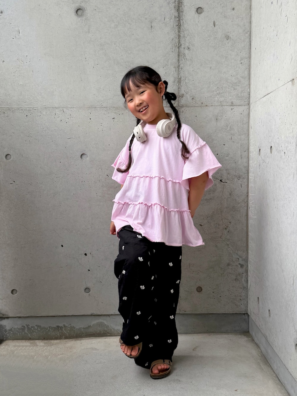 ピンク系のTシャツ/カットソー、ブラック系のその他パンツ、ベージュ系のサンダルを着用したキッズの春コーディネートの1枚目の写真