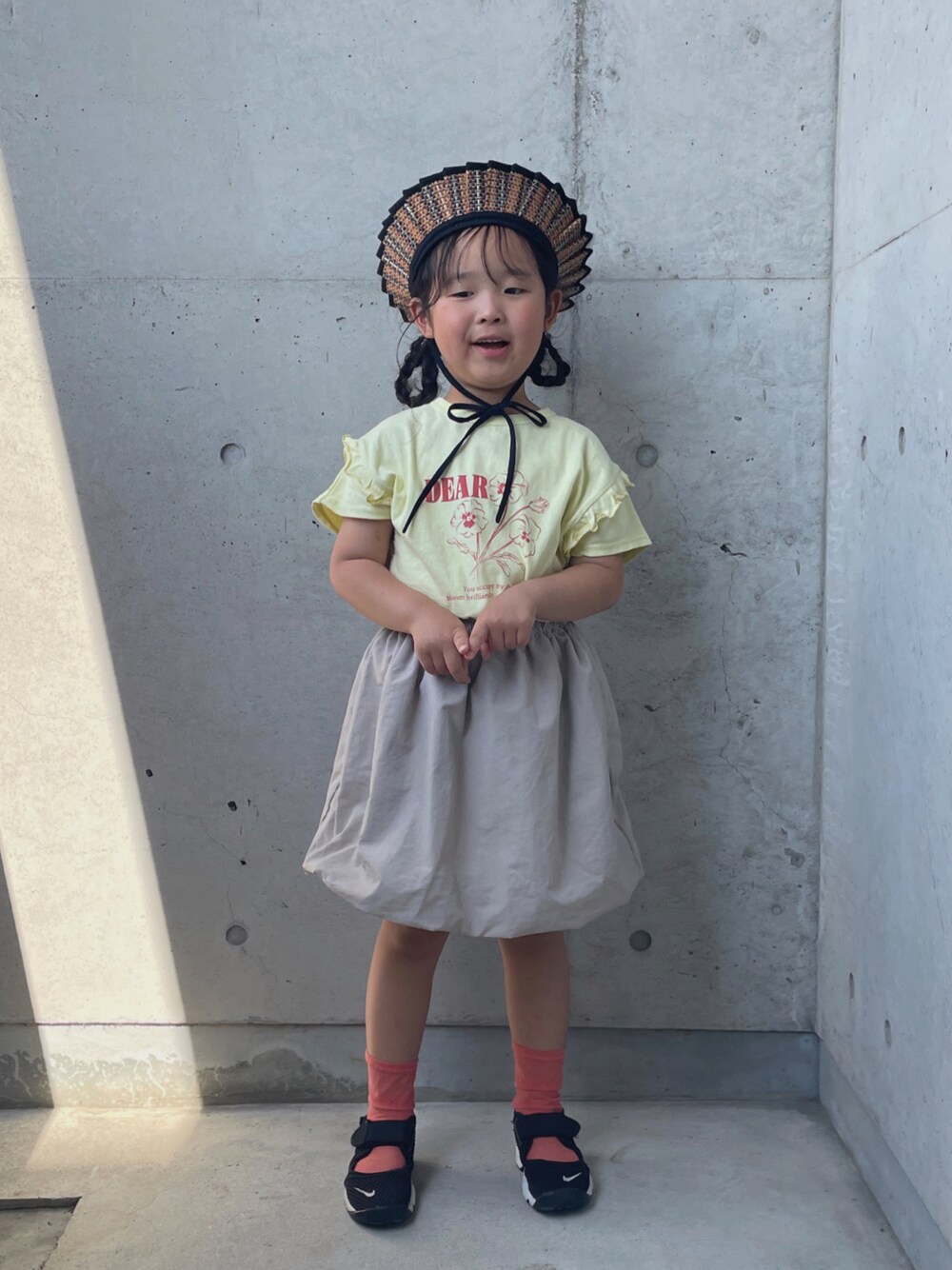 ブラック系のスニーカー、ベージュ系のTシャツ/カットソー、ベージュ系のスカートを着用したキッズの夏コーディネートの1枚目の写真