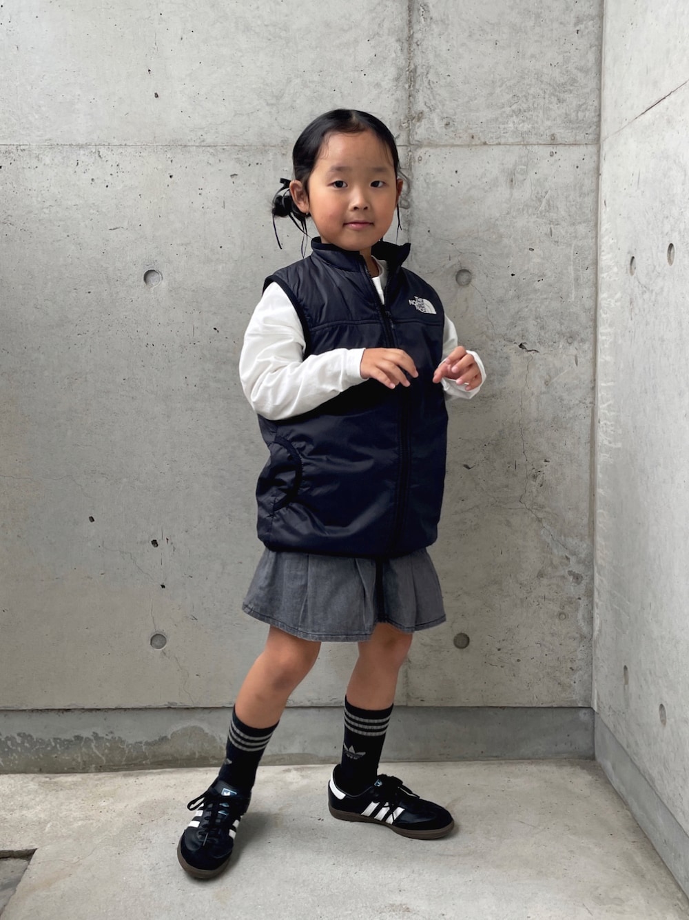 「モノトーン、ベスト、プリーツスカート、キッズコーデ、キッズファッション、ブラックコーデ、シンプルコーデ、ロンT、ロゴT、スニーカー、adidas、THE NORTH FACE、ヘアアレンジ」｜「green label relaxingのTJ 裾タック スカート（ブラックデニム） / キッズ  100cm-130cm（スカート、グレー系）」を使った、ioooさん（キッズ・110cm）の秋コーディネートの1枚目の写真