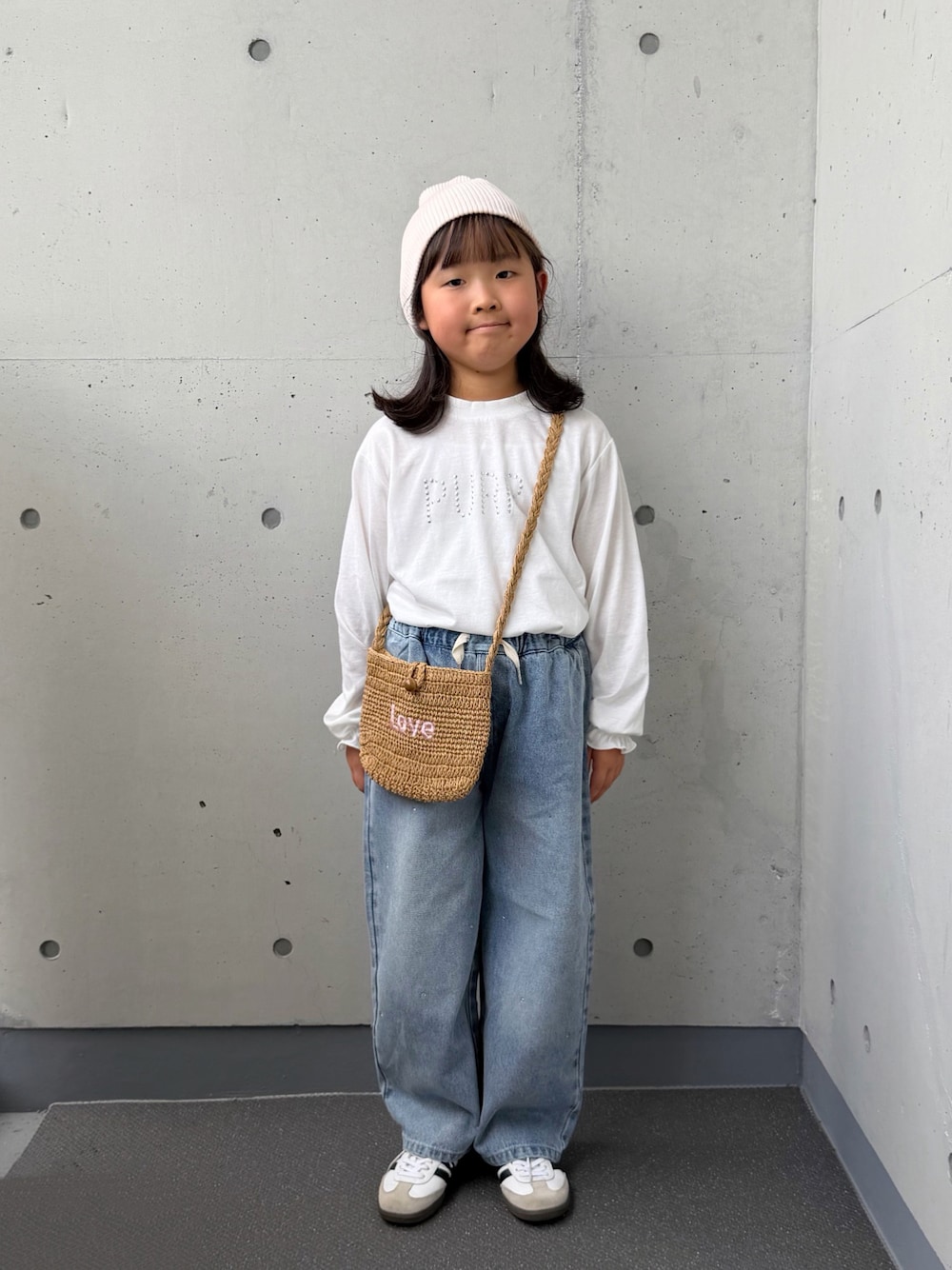 ベージュ系のショルダーバッグ、ホワイト系のTシャツ/カットソー、ブルー系のデニムパンツを着用したキッズの秋コーディネートの1枚目の写真