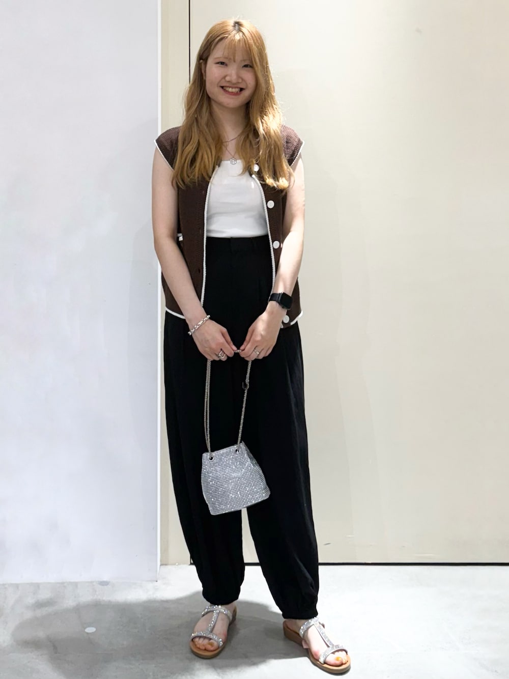 ブラウン系のベスト、ブラック系のその他パンツ、ホワイト系のショルダーバッグを着用したレディースの夏コーディネートの1枚目の写真