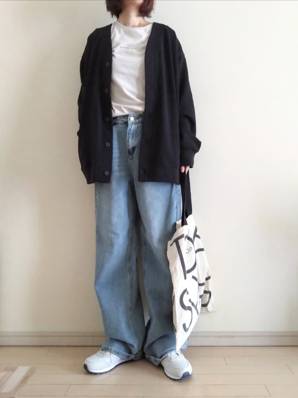 ブラック系のカーディガン/ボレロ、ベージュ系のTシャツ/カットソー、ブルー系のデニムパンツを着用したレディースの春コーディネートの1枚目の写真