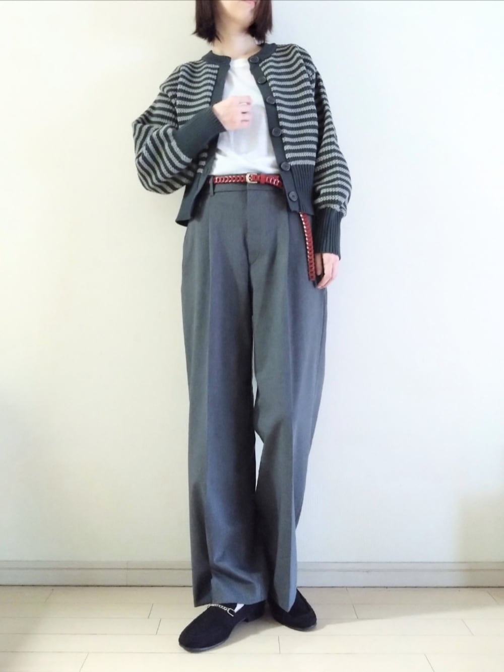 グレー系のカーディガン/ボレロ、ホワイト系のTシャツ/カットソー、グレー系のスラックスを着用したレディースの秋コーディネートの1枚目の写真
