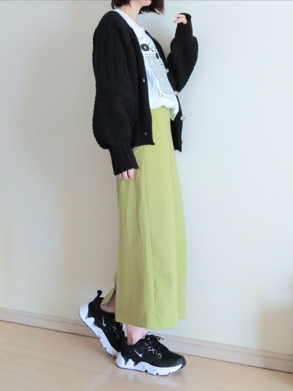 グリーン系のスカート、ブラック系のカーディガン/ボレロ、ホワイト系のTシャツ/カットソーを着用したレディースの秋コーディネートの1枚目の写真
