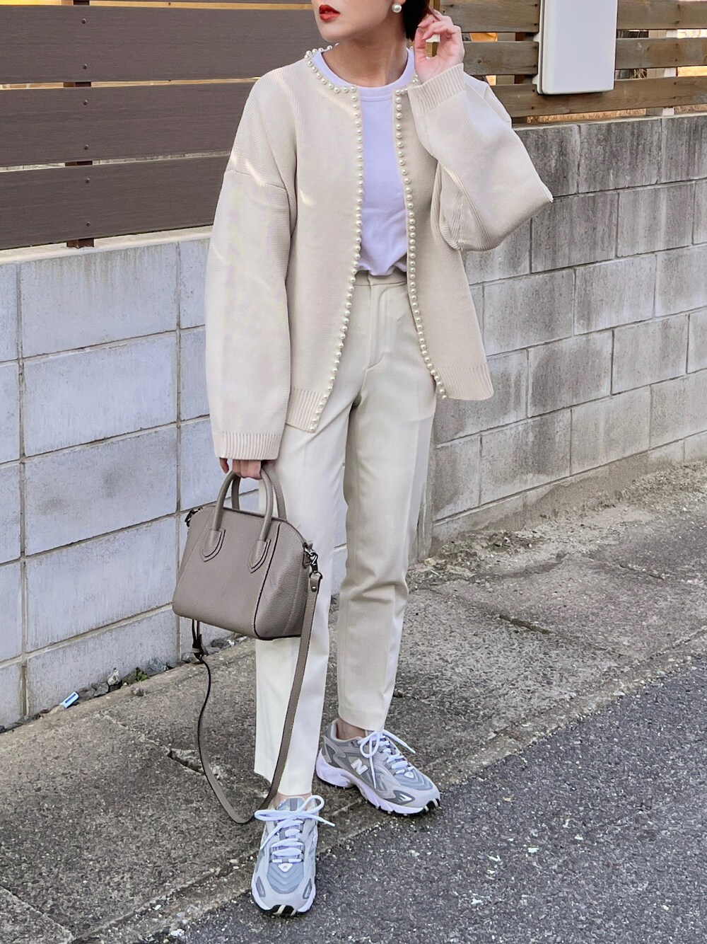 ホワイト系のカーディガン/ボレロ、グレー系のスニーカー、グレー系のハンドバッグを着用したレディースの冬コーディネートの1枚目の写真