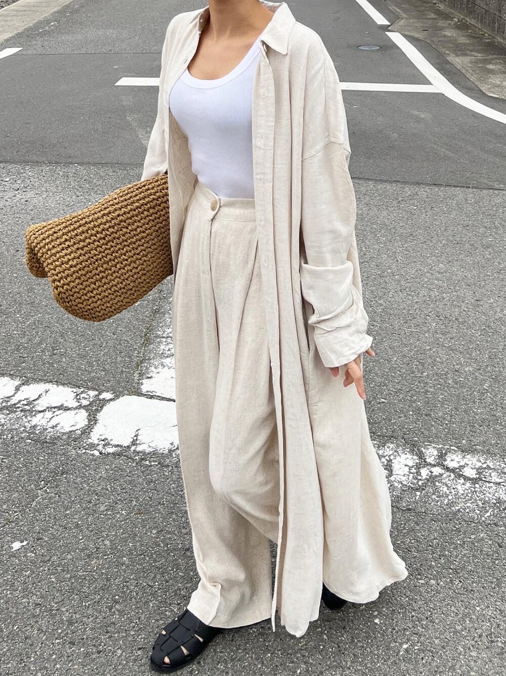 ベージュ系のかごバッグ、ベージュ系のシャツワンピース、ブラック系のサンダルを着用したレディースの春コーディネートの1枚目の写真