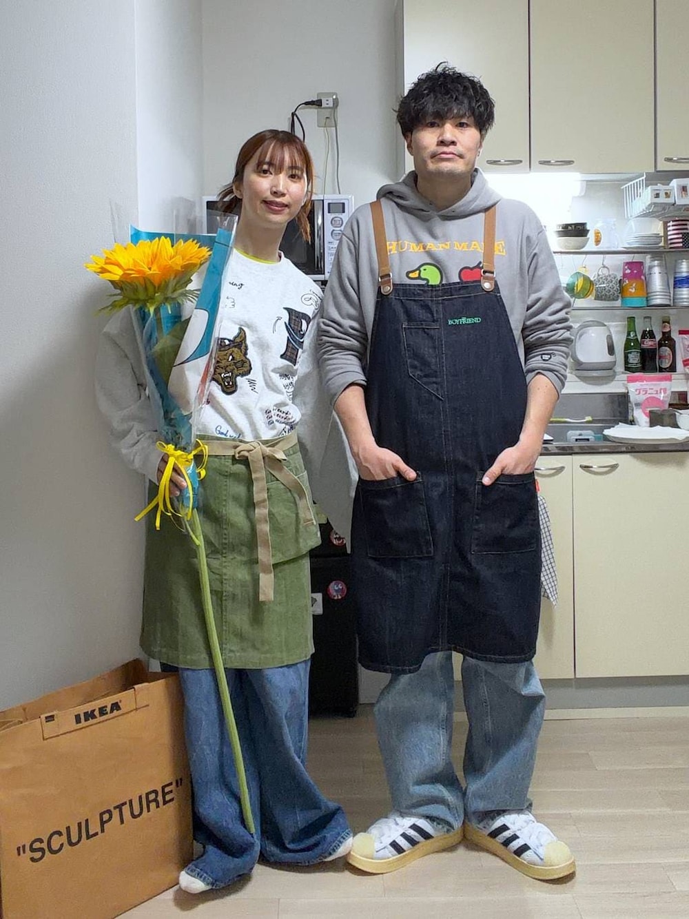 ブルー系のエプロンを着用したレディースの春コーディネートの1枚目の写真