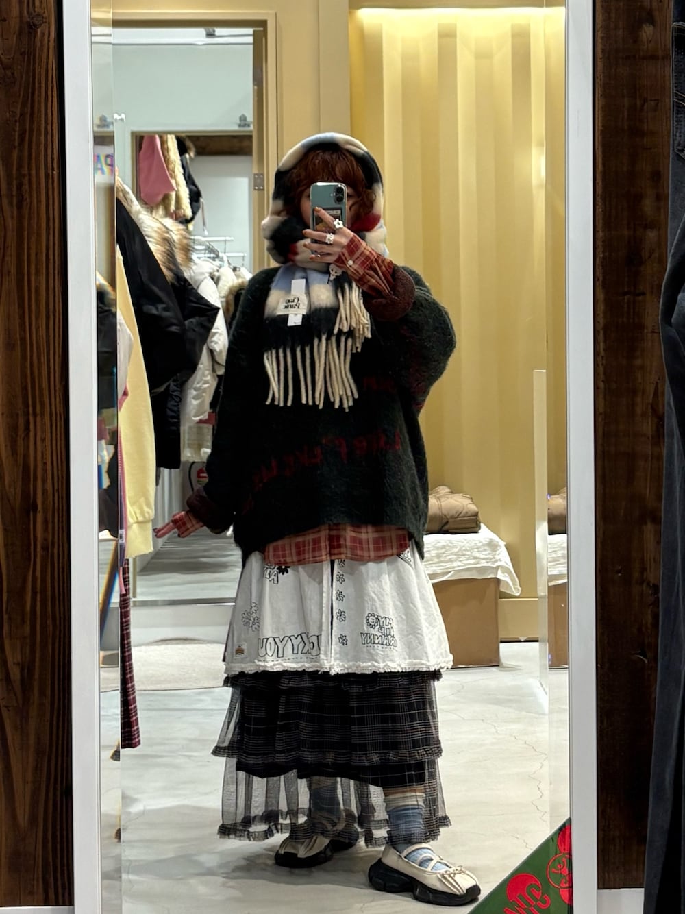 グリーン系のニット/セーター、ホワイト系のマフラーを着用したレディースの冬コーディネートの1枚目の写真