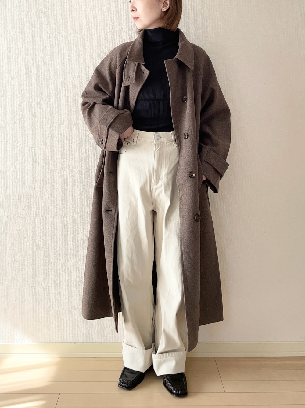 ブラウン系のステンカラーコート、ブラック系のニット/セーター、ホワイト系のその他パンツを着用したレディースの秋コーディネートの1枚目の写真