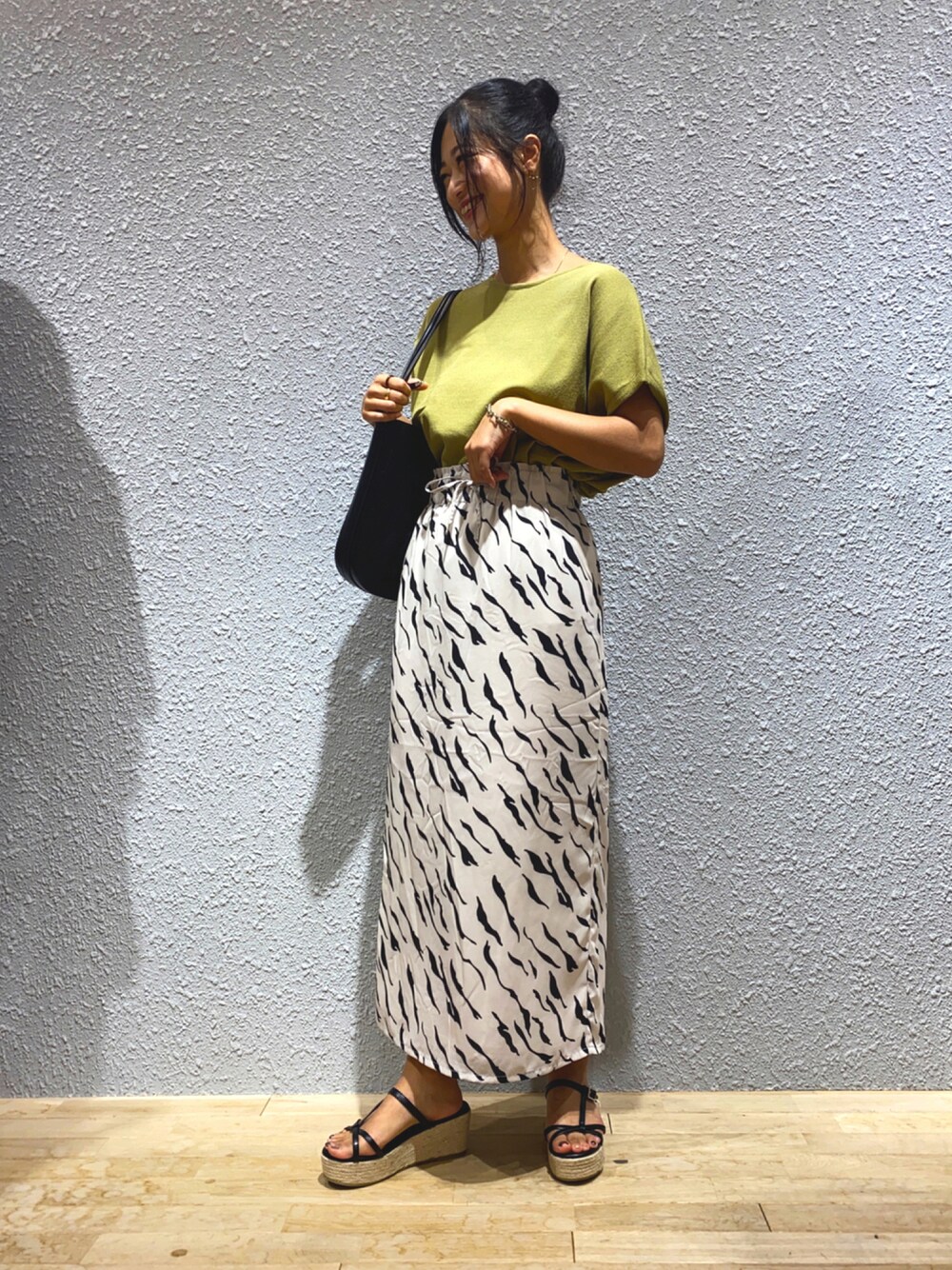 イエロー系のニット/セーター、ホワイト系のスカート、ブラック系のサンダルを着用したレディースの夏コーディネートの1枚目の写真