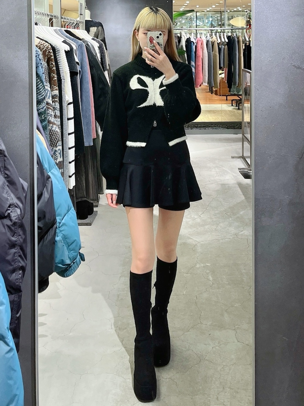 ブラック系のニット/セーター、ブラック系のスカート、その他のブーツを着用したレディースの冬コーディネートの1枚目の写真