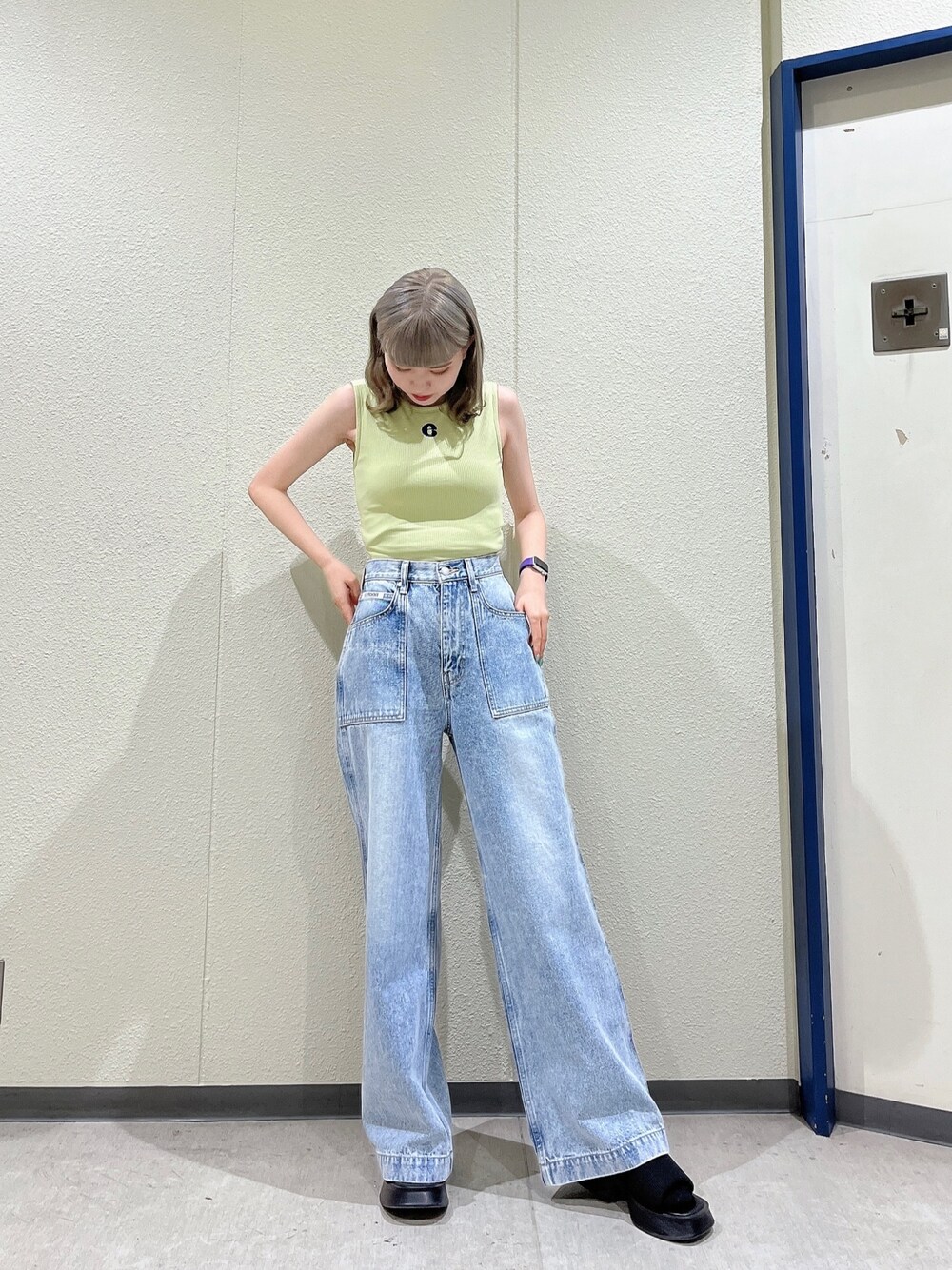 イエロー系のタンクトップ、ブルー系のデニムパンツ、ブラック系のサンダルを着用したレディースの夏コーディネートの1枚目の写真