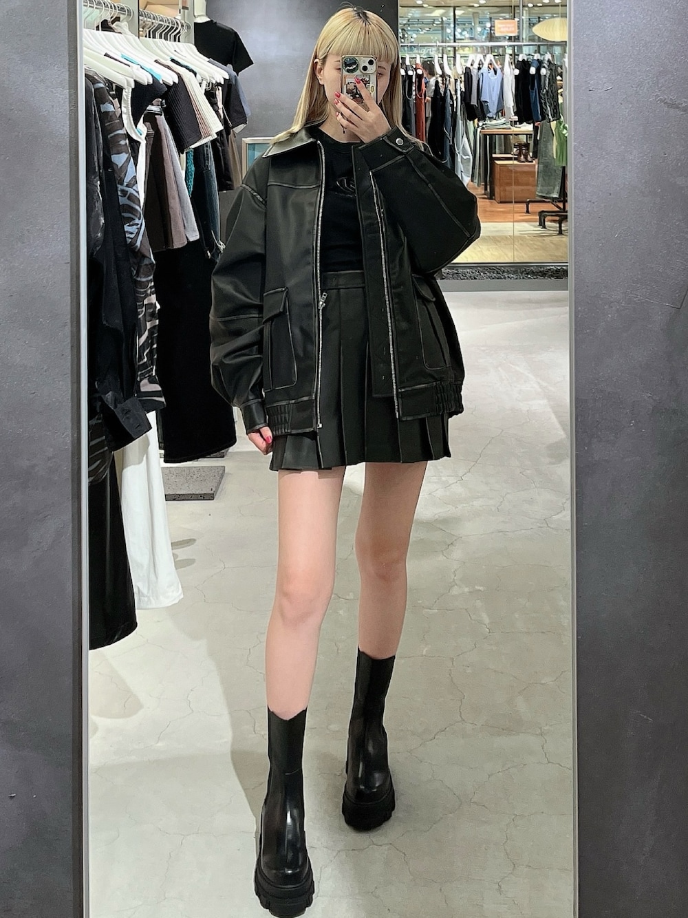 ブラック系のスカート、ブラック系のブルゾン、ブラック系のブーツを着用したレディースの夏コーディネートの1枚目の写真