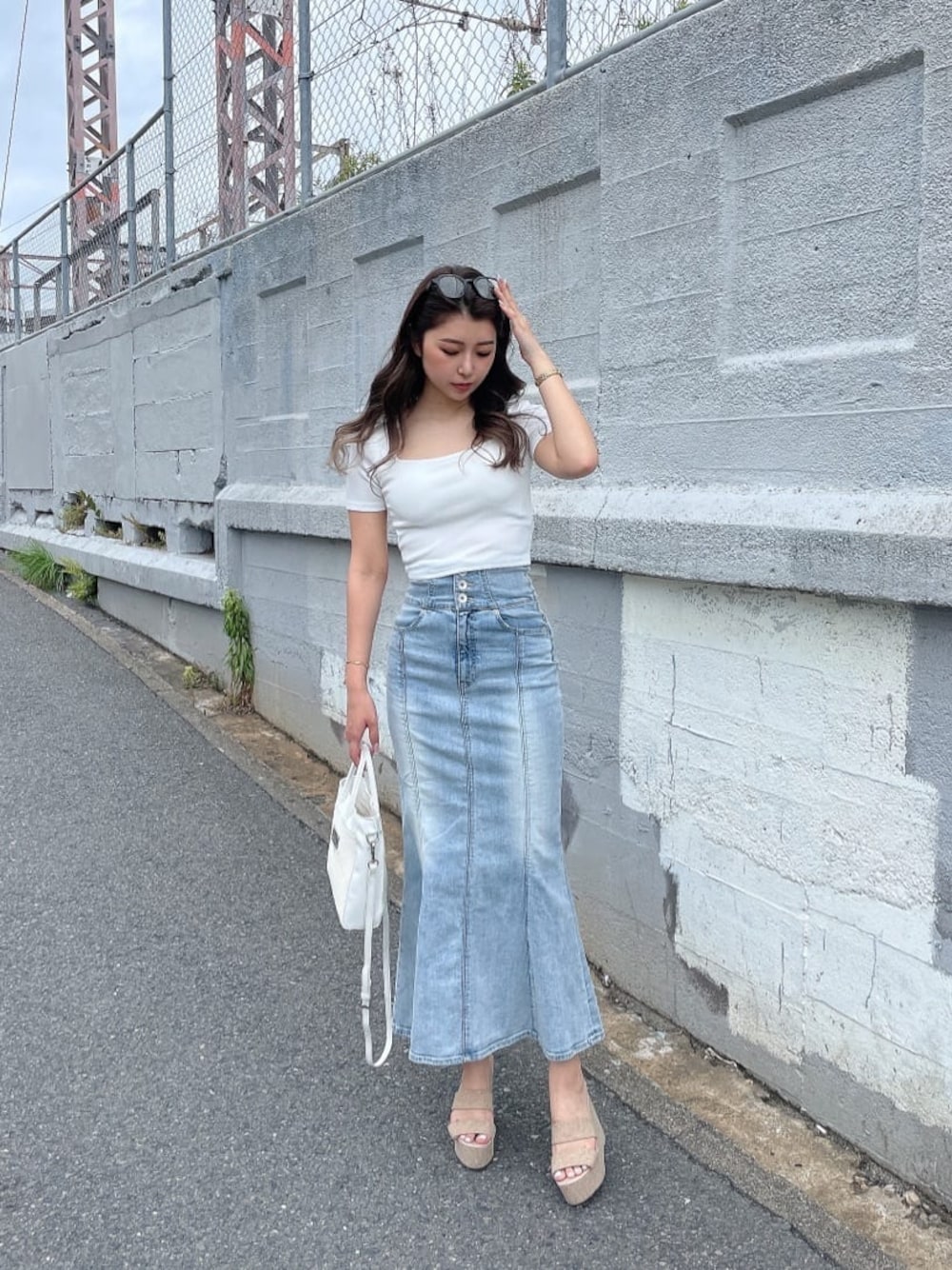 ホワイト系のハンドバッグ、ブルー系のデニムスカート、ホワイト系のTシャツ/カットソーを着用したレディースの夏コーディネートの1枚目の写真