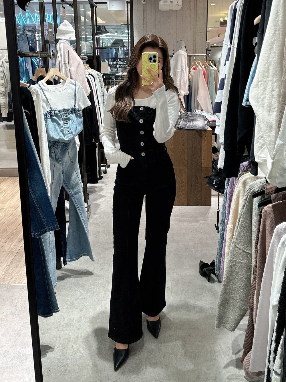 ブラック系のサロペット/オーバーオール、ホワイト系のニット/セーター、ブラック系のパンプスを着用したレディースの春コーディネートの1枚目の写真