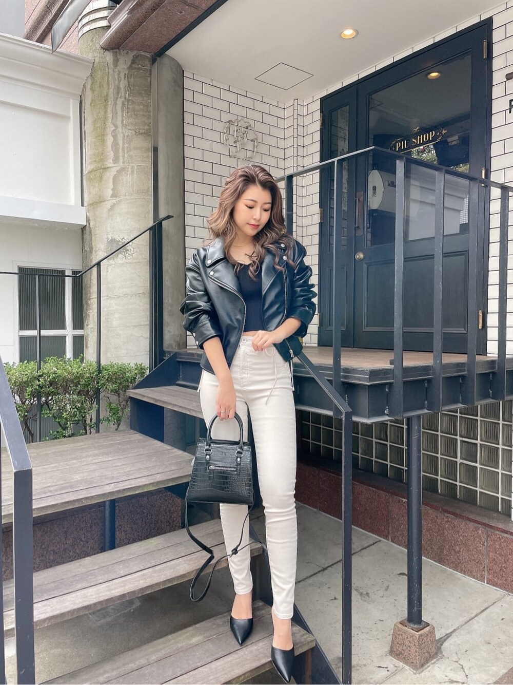 ブラック系のハンドバッグ、ブラック系のパンプス、ブラック系のライダースジャケットを着用したレディースの冬コーディネートの1枚目の写真