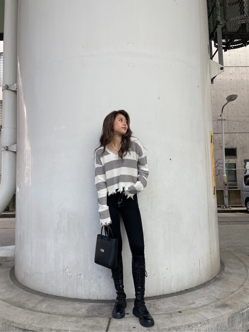 ブラック系のショルダーバッグ、ブラック系のデニムパンツ、グレー系のニット/セーターを着用したレディースの秋コーディネートの1枚目の写真