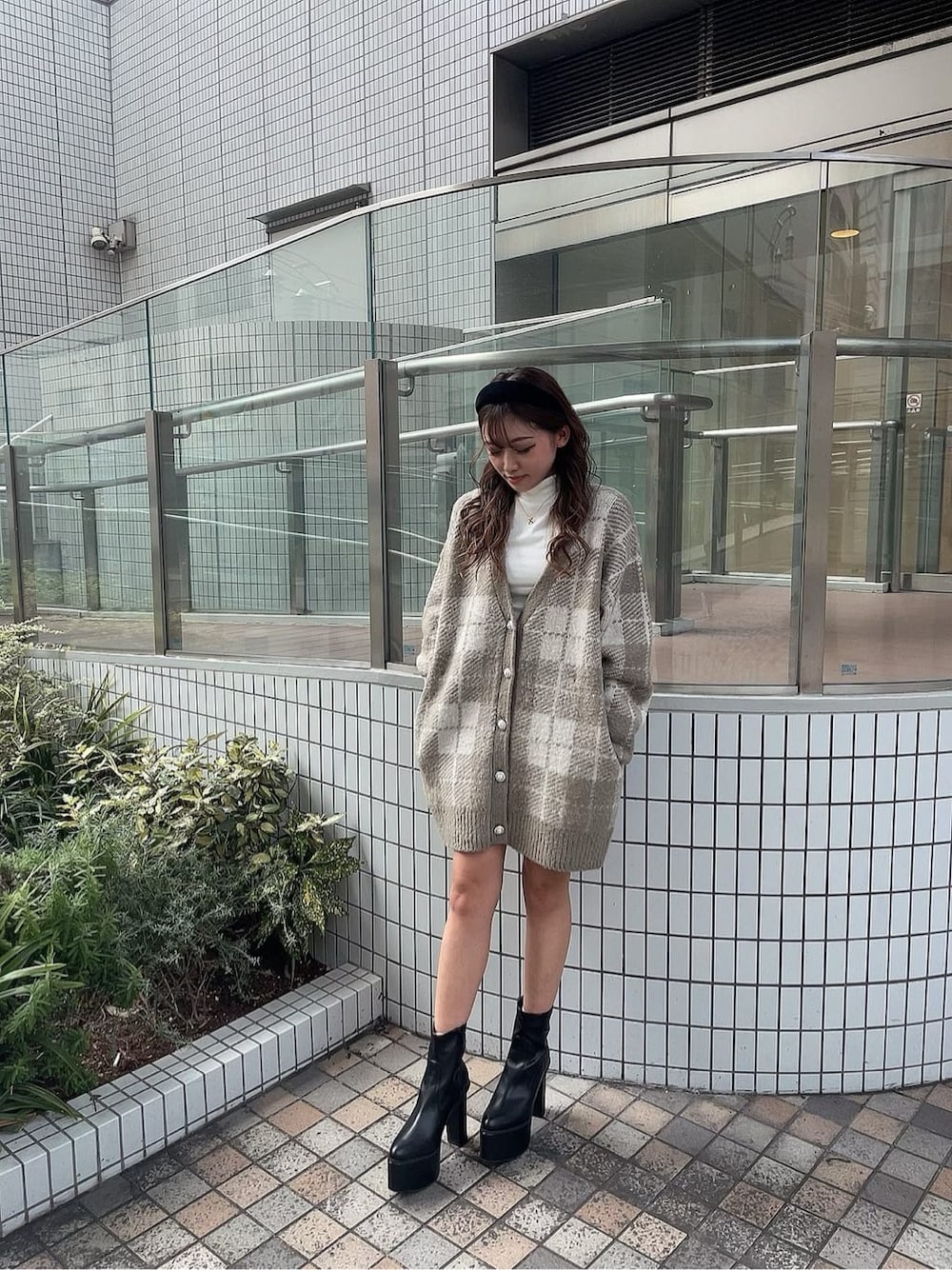 ブラック系のスカート、ホワイト系のTシャツ/カットソー、ブラック系のブーツを着用したレディースの秋コーディネートの1枚目の写真