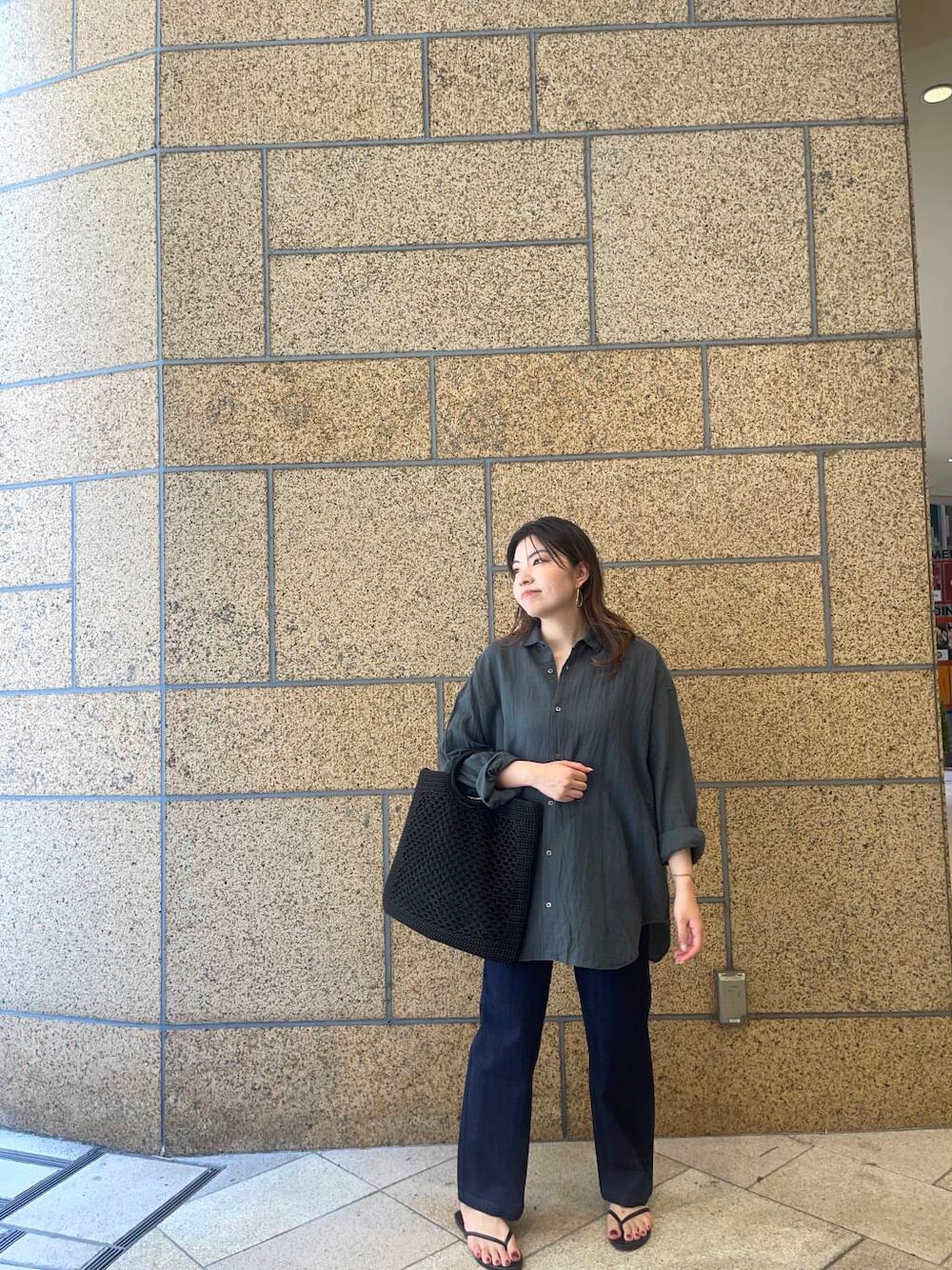 ブラック系のサンダル、ブルー系のデニムパンツ、ブラック系のトートバッグを着用したレディースの夏コーディネートの1枚目の写真